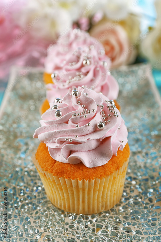Tasty cupcakes on plate, on color wooden background