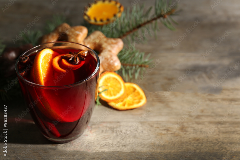 Mulled wine with spices and biscuits on wooden background