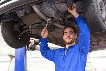 Wall Mural - Young attractive mechanic working on a car at the garage