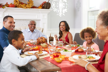 Family With Grandparents Enjoying Thanksgiving Meal At Table