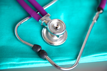 A stethoscope shaping a heart and a clipboard on a medical uniform, closeup