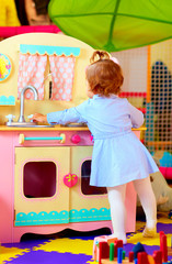 little hostess at toy kitchen in kindergarten