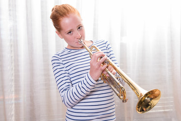 red haired teenage girl playing the trumpet