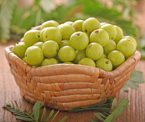 Poster - Indian gooseberry  in wooden bowl on a wooden floor.