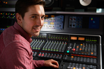 Wall Mural - Engineer Sitting At Mixing Desk In Recording Studio