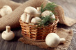 Champignon mushrooms, a basket, dill and sacking mat on wooden background