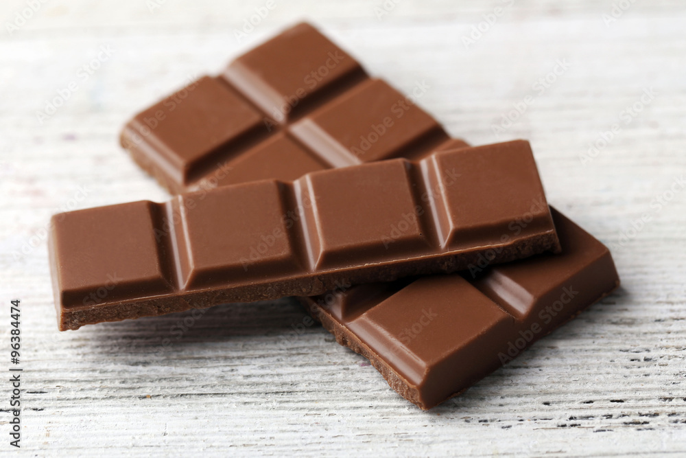 Black chocolate pieces on color wooden background