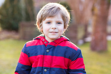 Wall Mural - Portrait of happy little kid boy in red jacket, outdoors