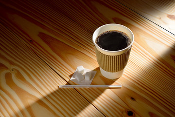 Wall Mural - Paper cup of coffee in the morning light on wooden background