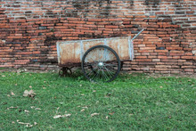 Old Wheelbarrow In Front Of A Brick Wall