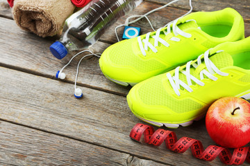 Shoe, water, tape measure and headphones on grey wooden backgrou