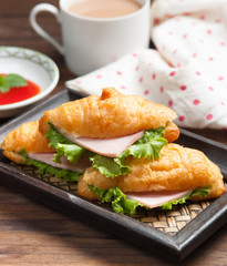 Fresh croissant ham and salad leaf with sauce on dark wooden bac