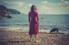 Woman In Red Dress On Beach With Dog
