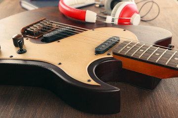 Electric guitar with headphones on wooden table close up