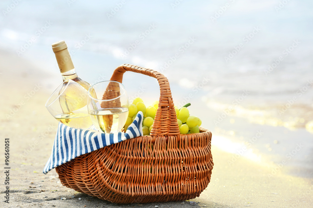 Picnic basket with bottle of wine on sand beach