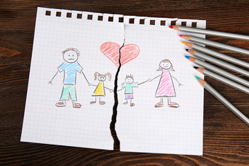 Torn apart drawing of a family on wooden background