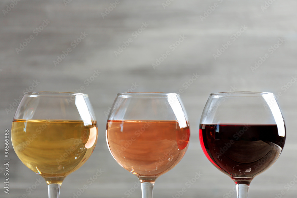 Wine glasses in a row on grey background, close up