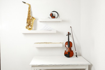 Wall Mural - Musical instruments and headphones on decorated shelves against white wall background