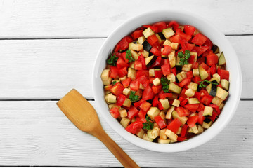 Ratatouille, stewed vegetable dish with tomatoes, zucchini, eggplant before cooking, on wooden background