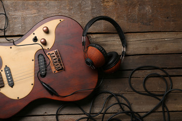 Wall Mural - Electric guitar and headphones on wooden background