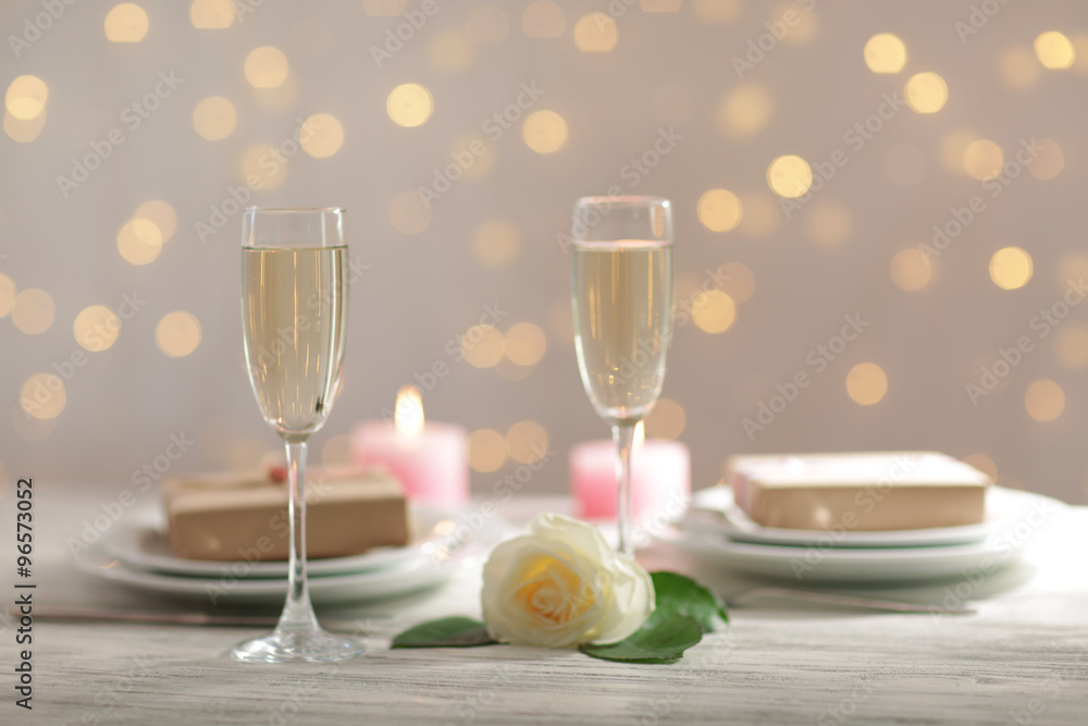 Glasses of wine and a white rose, on blurred background