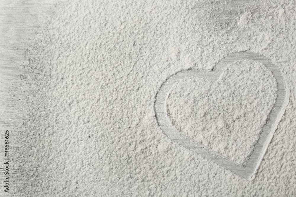 Heart of flour on wooden background