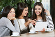 © Africa Studio - Beautiful friends look at something in tablet during drinking coffee in cafe