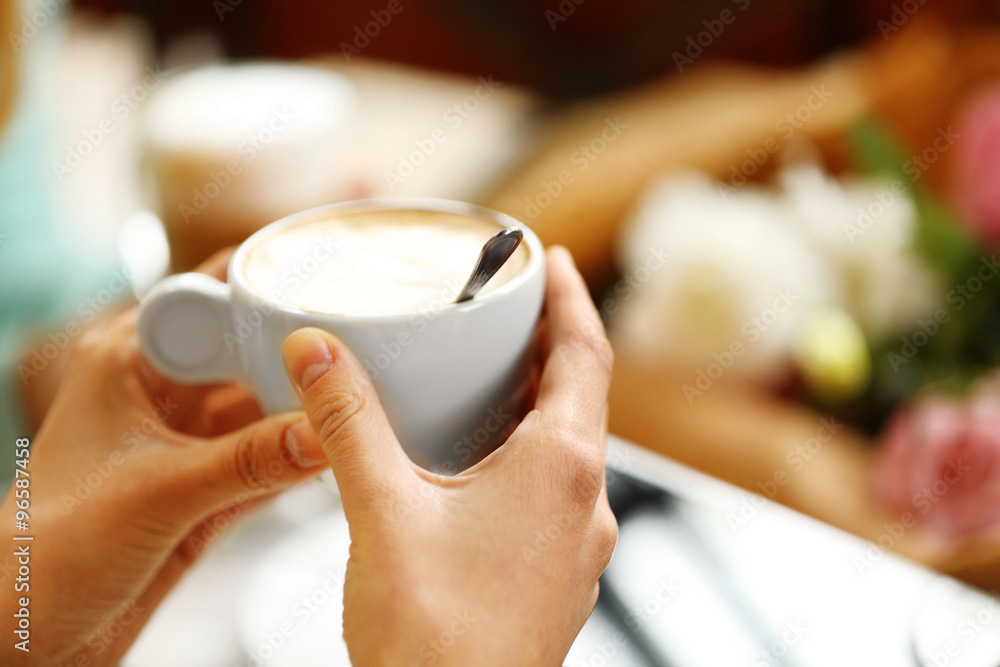 Woman holding cup of coffee in cafe