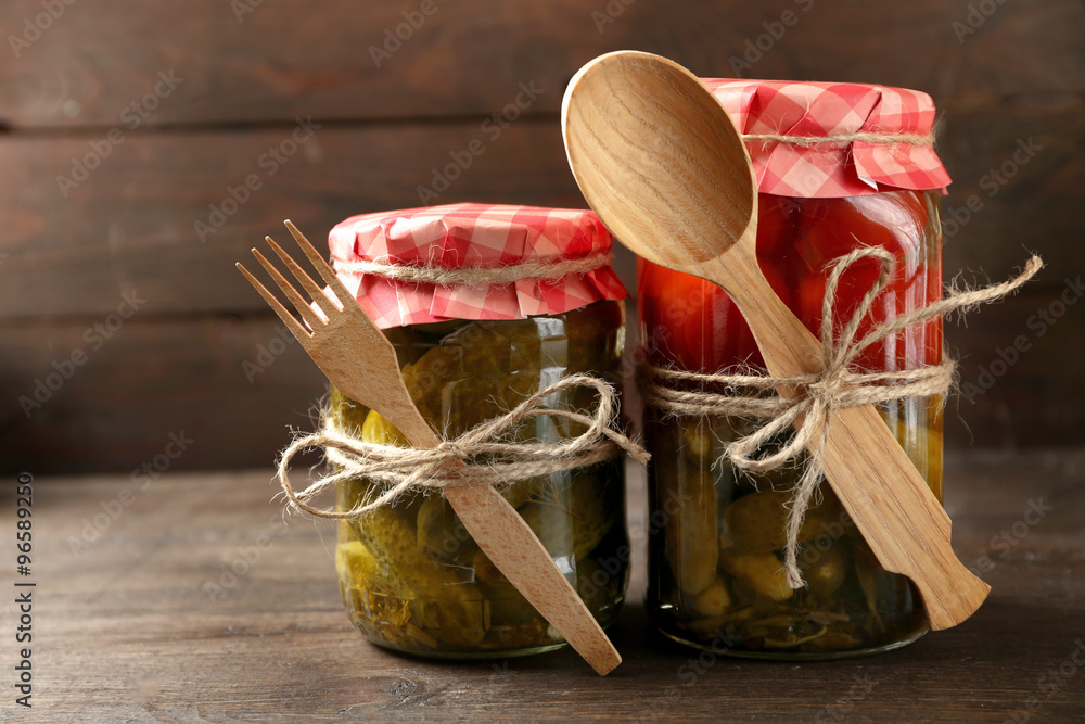Jars with pickled vegetables on wooden background