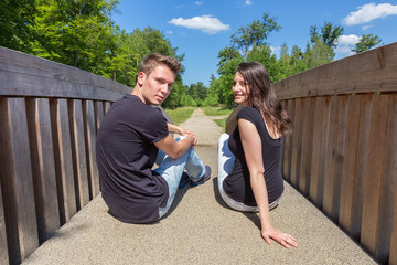 Young attractive dutch couple sitting on wooden bridge