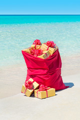 Canvas Print - Christmas sack full of wrapped gift boxes at tropical beach