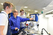 © industrieblick - Azubis und Lehrer in der technischen Berufsausbildung stehen an einer Drehmaschine