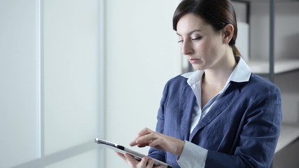 Wall Mural - Confident businesswoman using a touch screen digital tablet and smiling at camera, efficiency and technology concept