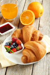 Wall Mural - Fresh tasty croissants with berries on grey wooden background