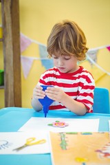 Wall Mural - Small boy using a bottle of glue