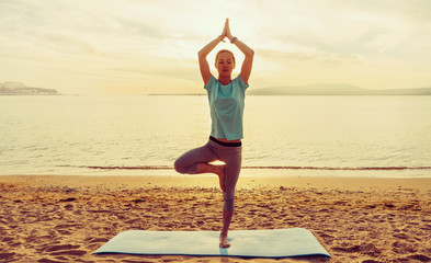 Wall Mural - Girl in yoga pose of tree on beach