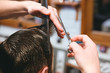 Barbers hands making haircut to man using comb and scissors