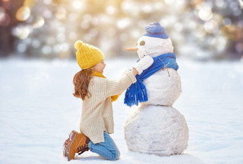 Wall Mural - girl playing with a snowman