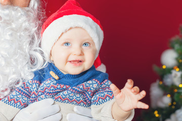 Closeup happy baby and Santa Claus waiting for gift, present.