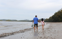 Grandfather With His Granddaughter  Walking On A Beach