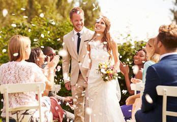 Wall Mural - Guests Throwing Confetti Over Bride And Groom At Wedding