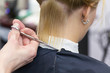 © Ravil Sayfullin - Hairdresser's hand holding scissors making haircut for a blonde female client