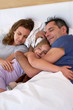 © Daxiao Productions - family holding each other and sleeping in bed