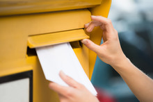 Woman's Hands Inserting Letter In Mailbox
