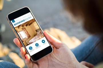 woman sitting in the street holding her smartphone with booking