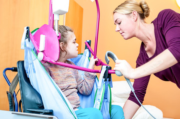 Disabled child being lifted into a wheelchair using special needs lifting equipment operated by a nurse / Disabled child being lifted into a wheelchair