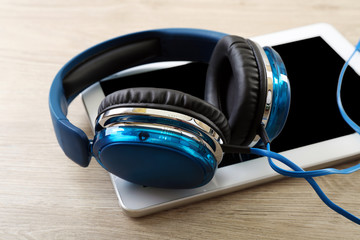 Headphones with tablet on wooden table close up