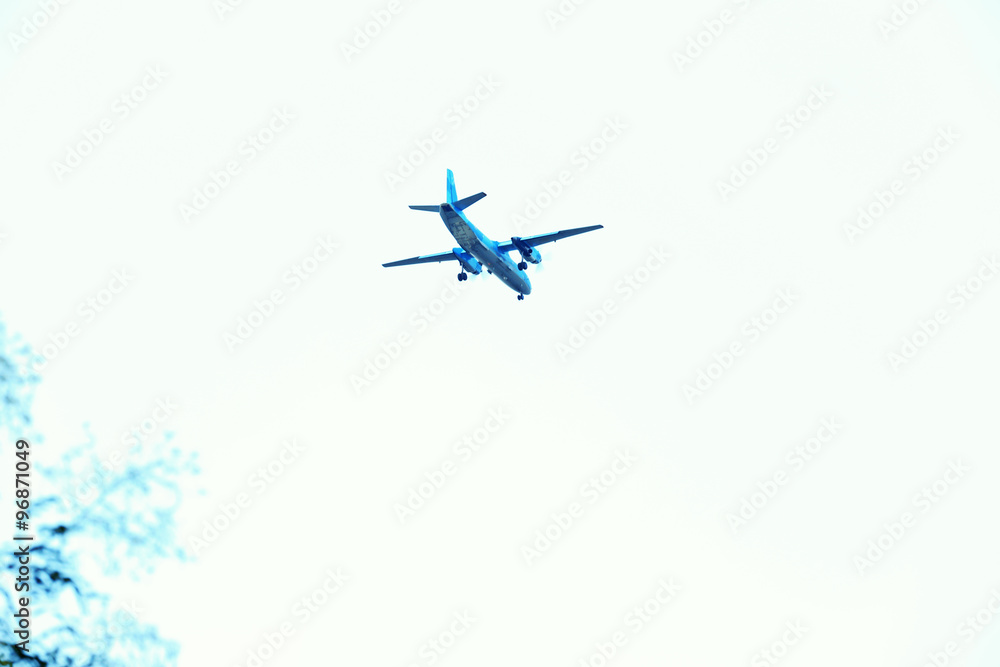 A grey airplane flying on a clear pale blue sky background