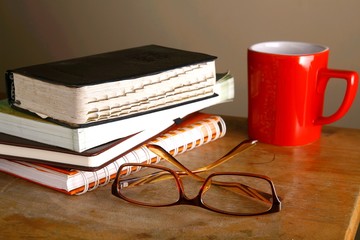Wall Mural - Eyeglasses, coffee mug and pile of books