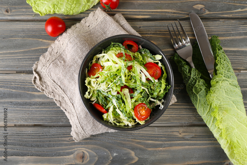 Savoy cabbage and tomato salad served in bowl on wooden table